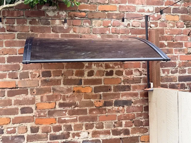 Curved translucent awning mounted on a red brick exterior wall.